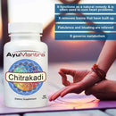 A bottle of AyuMantra Chitrakadi Vati tablets beside a person doing yoga at sunset with benefit text overlays.