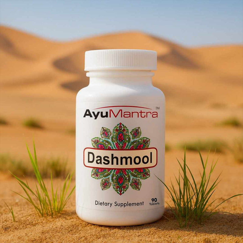 Ayumantra Dashmool tablets bottle standing on desert sand with small green grass tufts.