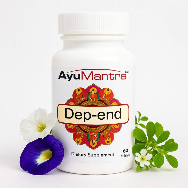 AyuMantra Dep-end tablets bottle beside herbs and flowers on white background for Ayurvedic mood support.