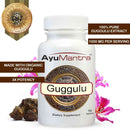 AyuMantra Guggulu tablets bottle with organic extract badge, guggul resin and flowers around the label.