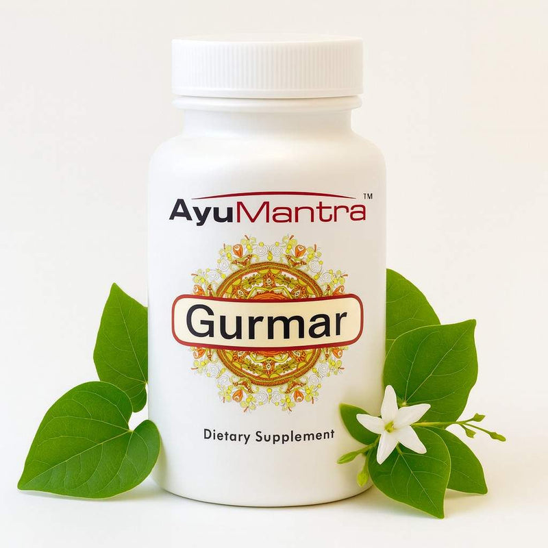 AyuMantra gurmar tablet bottle with fresh gurmar leaves and white flower beside it.