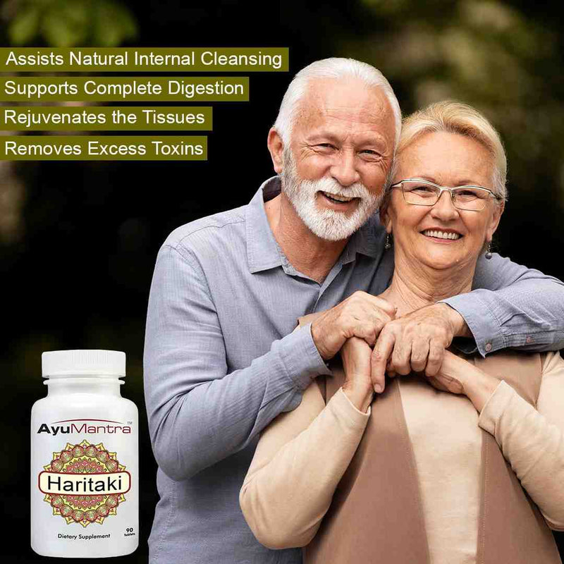 Senior couple smiling with AyuMantra Haritaki tablets bottle promoting digestion support