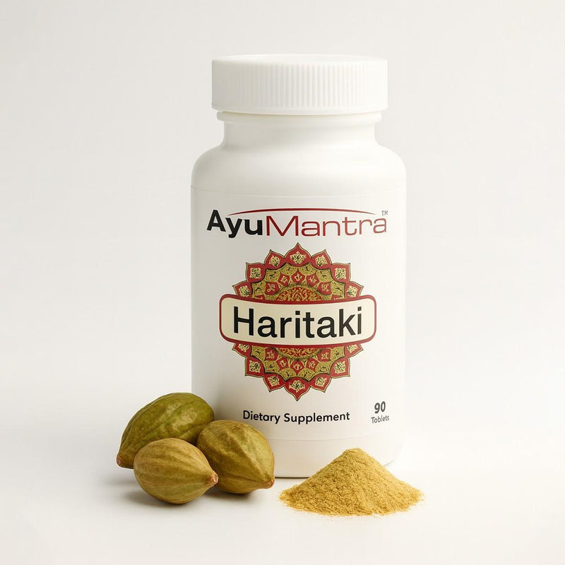 AyuMantra Haritaki tablets bottle with haritaki fruits and powder on a light studio background