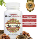 AyuMantra Haritaki tablets bottle with organic haritaki powder and fruits highlighting 1000 mg serving