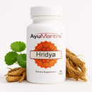 Ayumantra Hridya tablets bottle with green leaves and dried roots on a clean white background